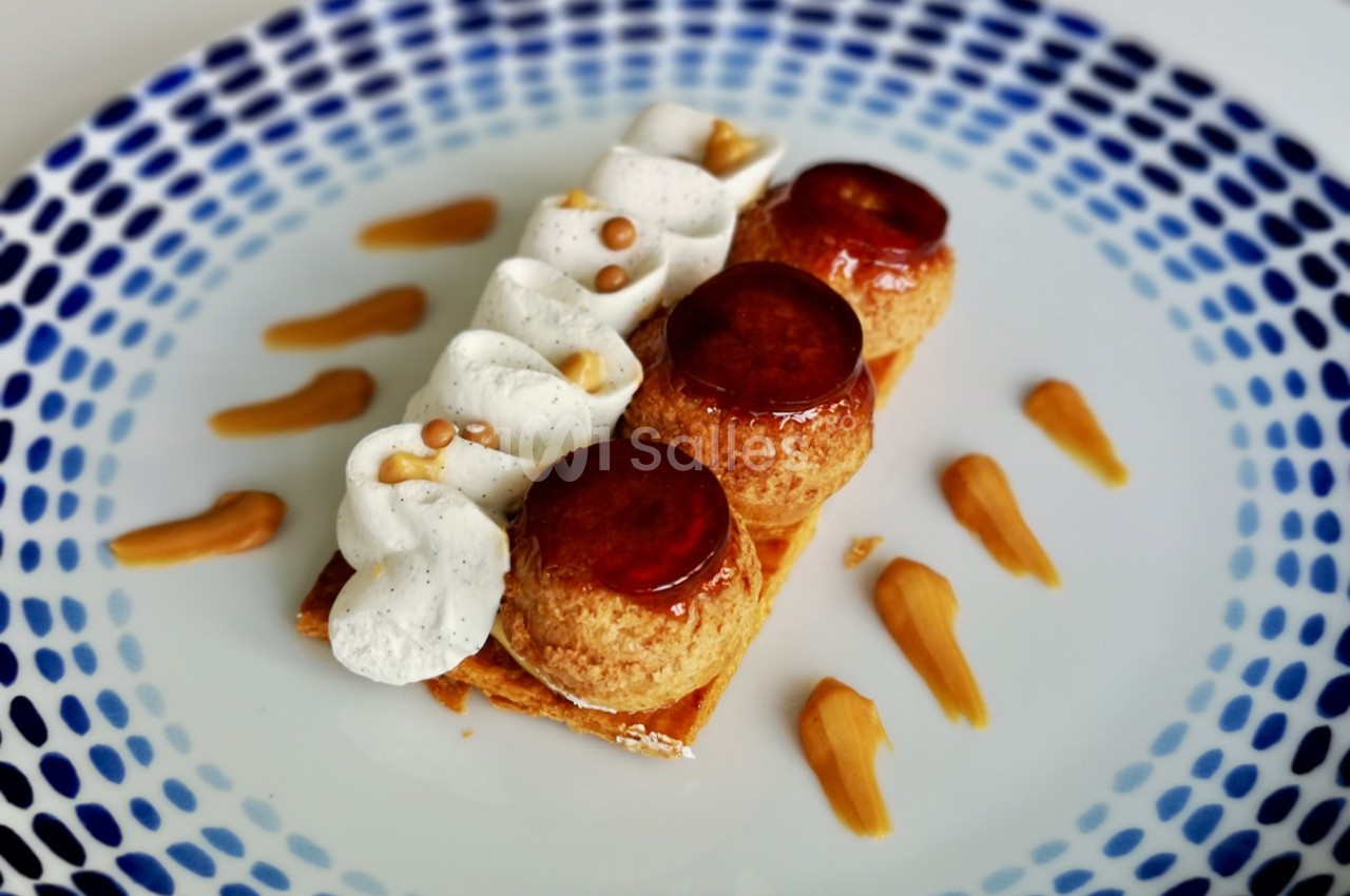 Dessert composé de choux caramélisés, chantilly vanillée et touches de caramel sur une assiette blanche décorée.