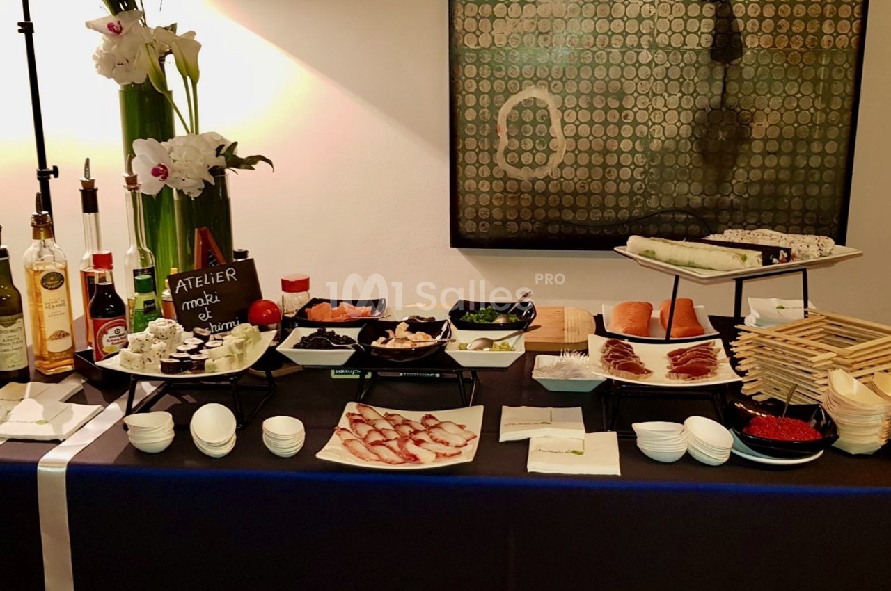 Buffet avec ingrédients variés pour la préparation de makis, incluant poissons, légumes, sauces et ustensiles.