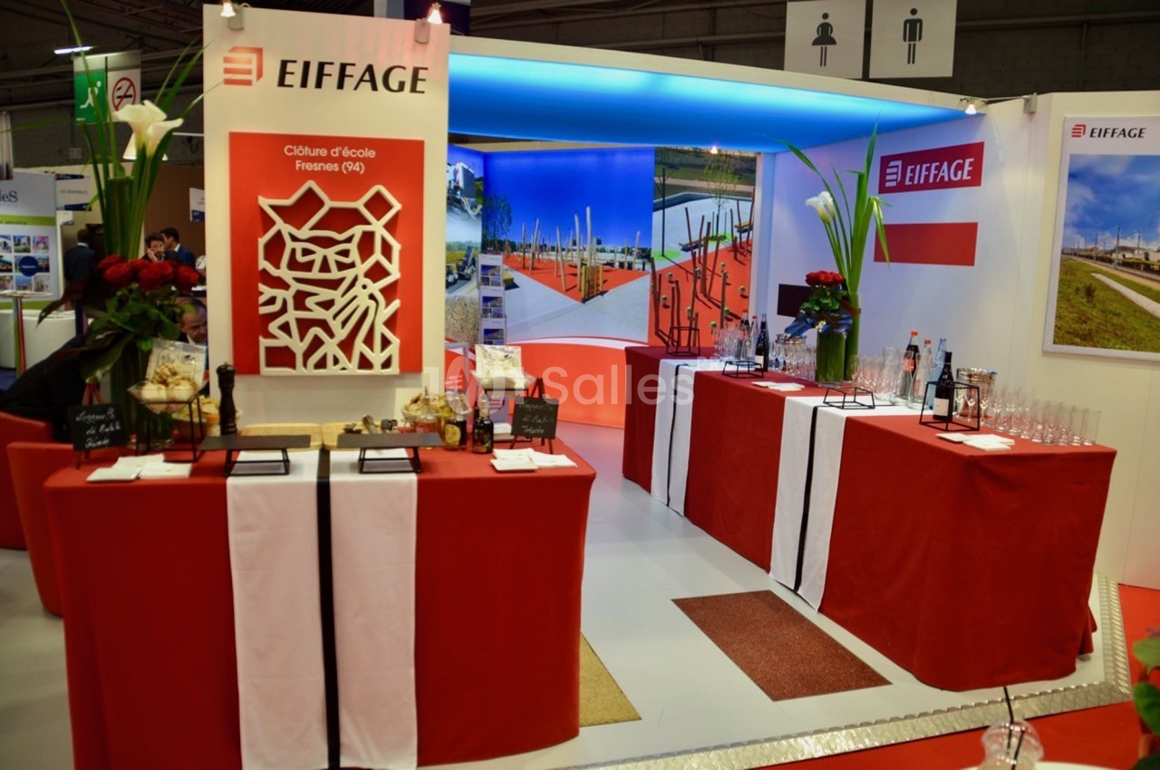 Stand d'exposition Eiffage avec présentoirs, décorations rouges et blanches, et panneaux illustrant des projets.
