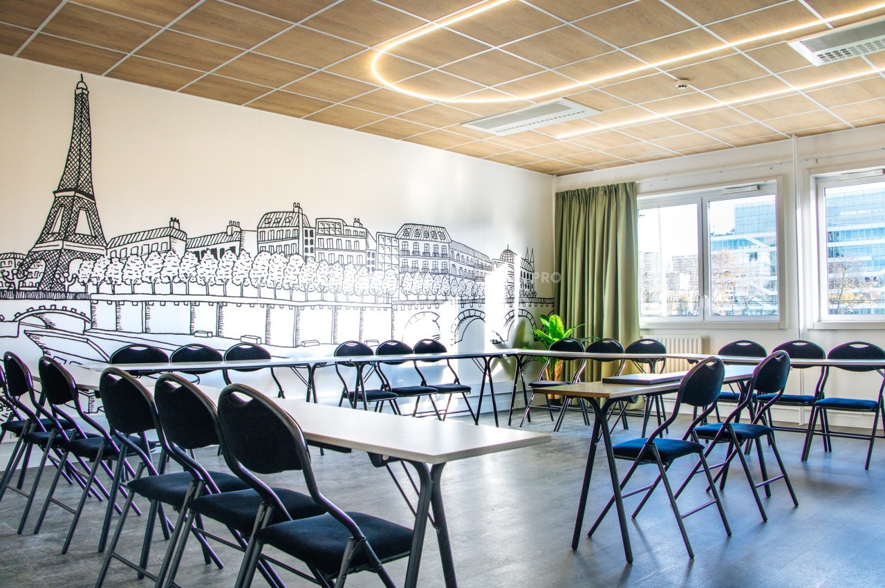 Salle de réunion lumineuse avec des chaises disposées en cercle, décorée d'une fresque représentant Paris.