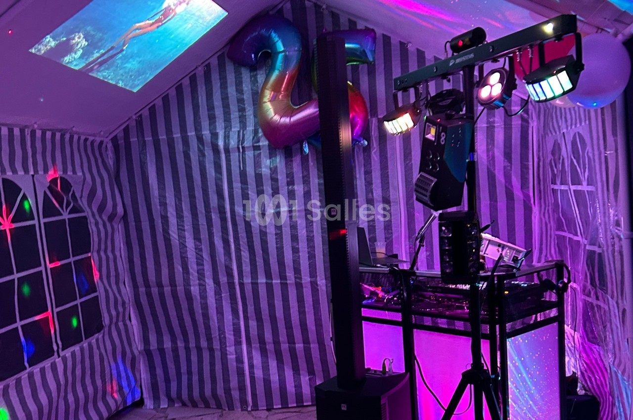 Installation de matériel de son et lumière dans une tente décorée pour une fête, avec un ballon en forme de ’25’.