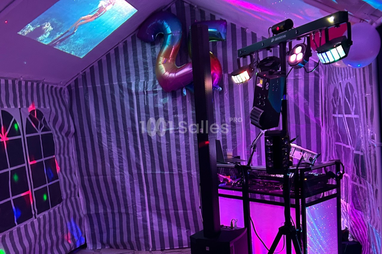 Installation de matériel de son et lumière dans une tente décorée pour une fête, avec des projections au plafond.