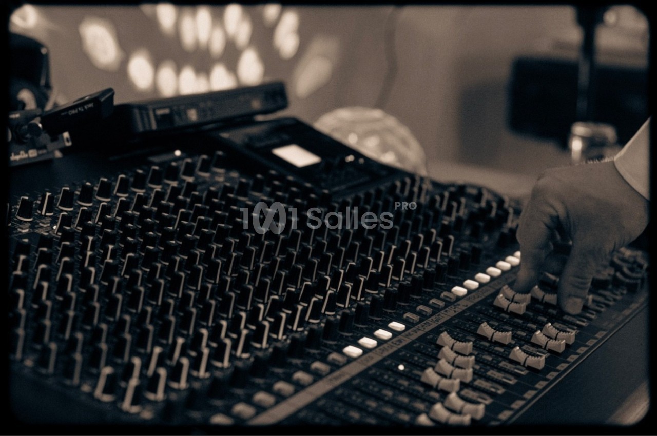 Main ajustant les curseurs d'une console de mixage audio dans un environnement faiblement éclairé.