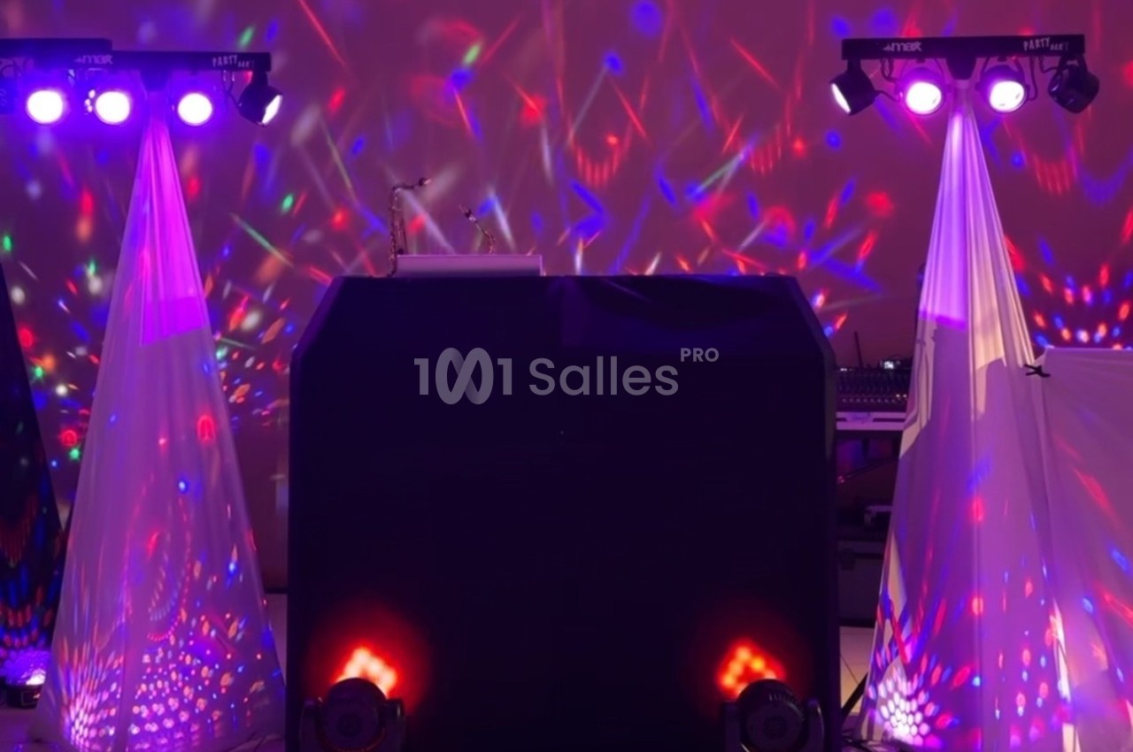 Installation de matériel de sonorisation et éclairage coloré avec projecteurs et effets lumineux dans une salle.