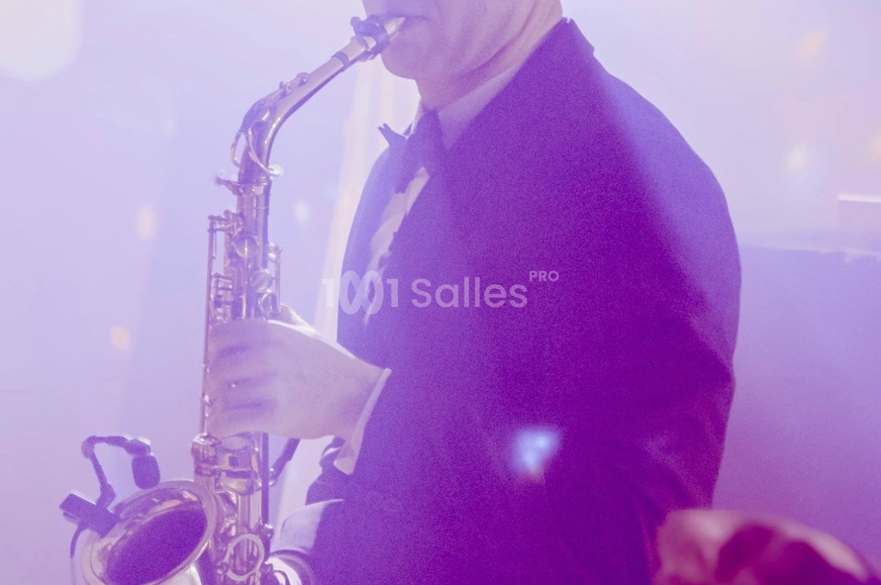 Un musicien en smoking joue du saxophone dans une ambiance lumineuse tamisée.