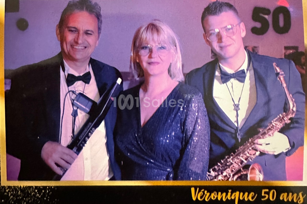 Trois personnes posent en tenue de soirée, deux hommes tenant des instruments de musique et une femme au centre.