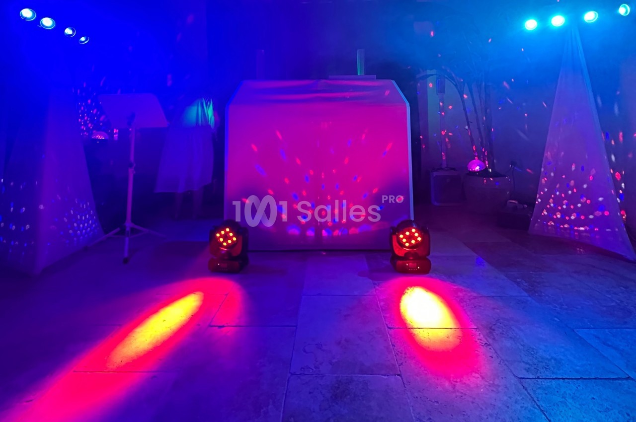 Jeu de lumières colorées projetées sur un sol et un mur dans une ambiance de soirée festive.