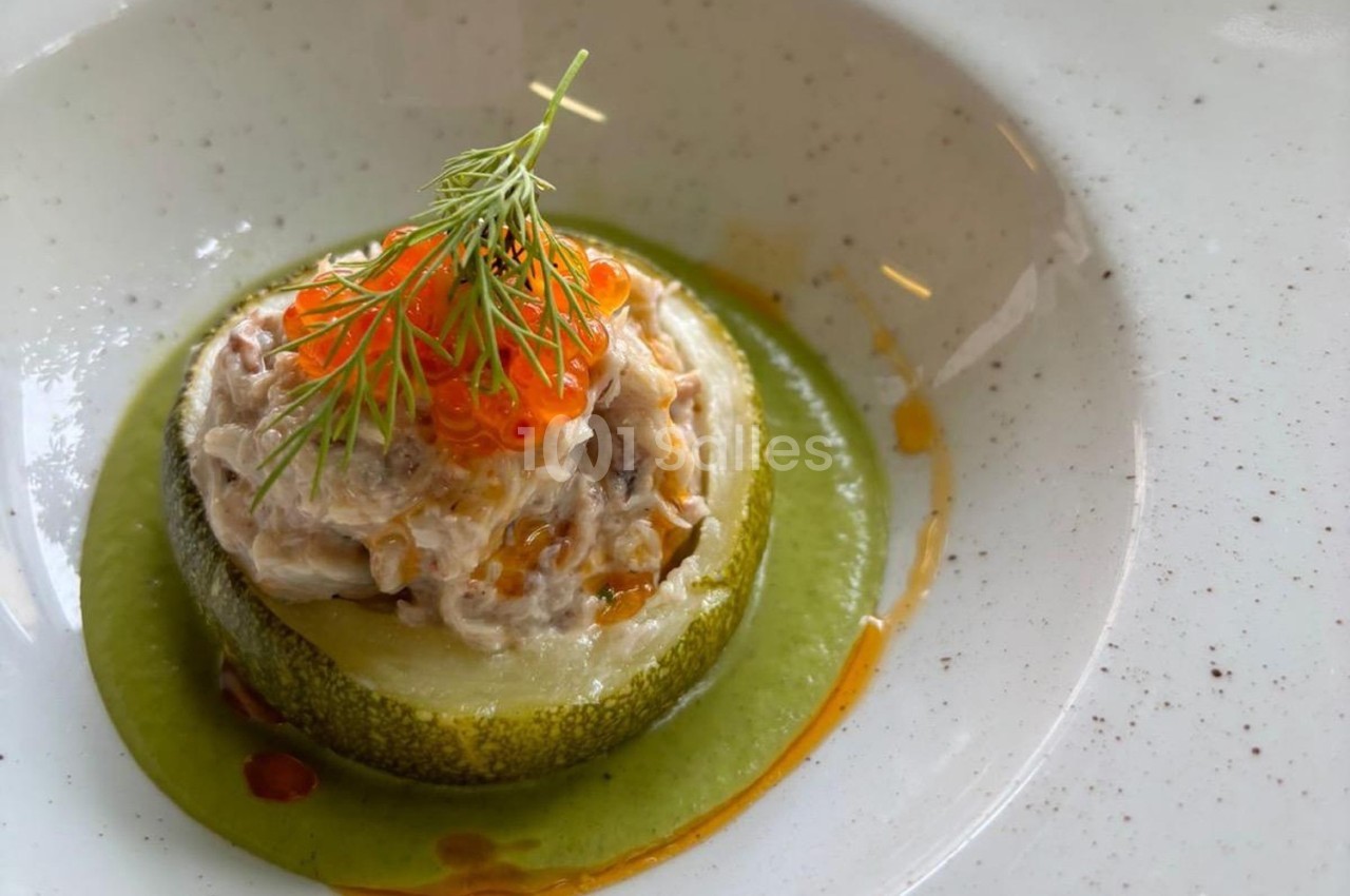 Tranche de courgette garnie de rillettes, œufs de poisson et aneth, posée sur une sauce verte.