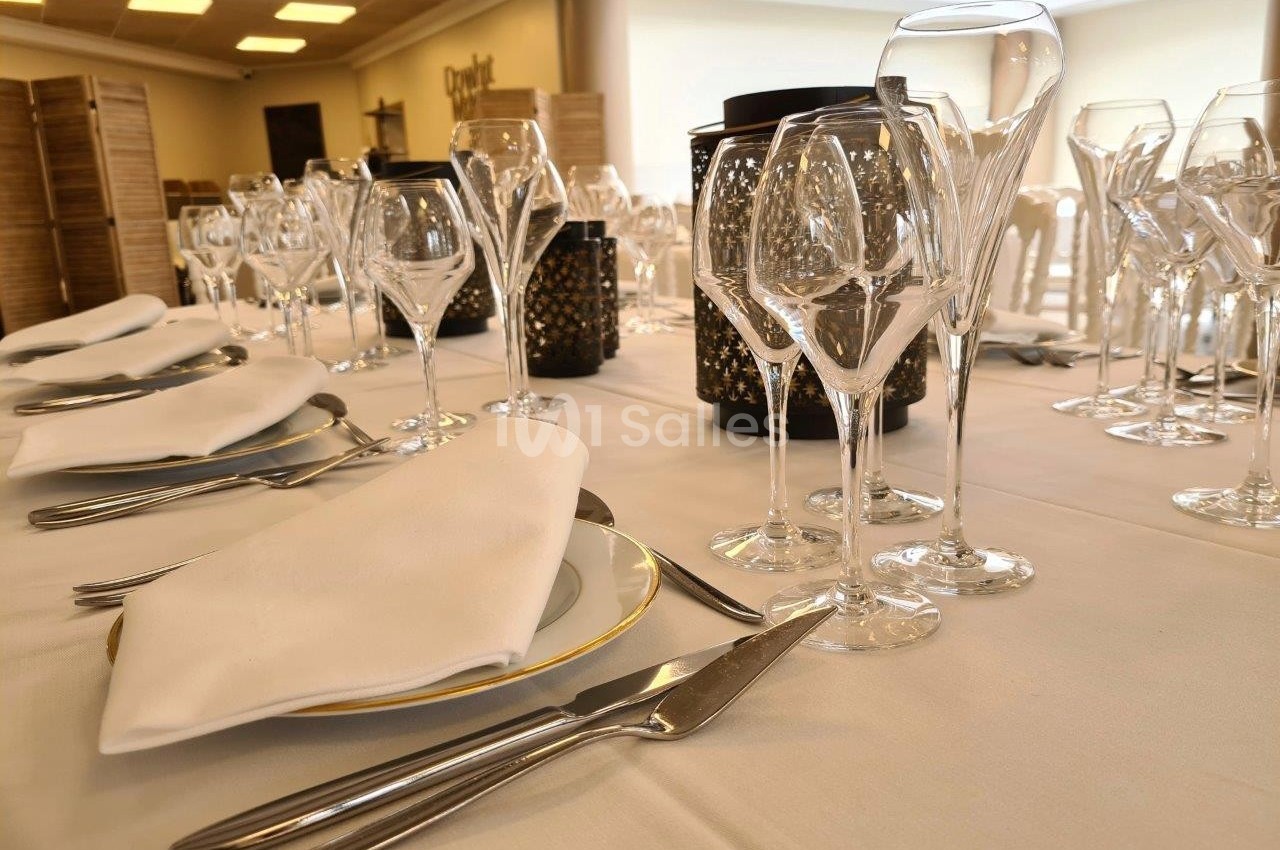 Table dressée avec nappes blanches, verres à vin et couverts alignés pour un événement ou un repas formel.
