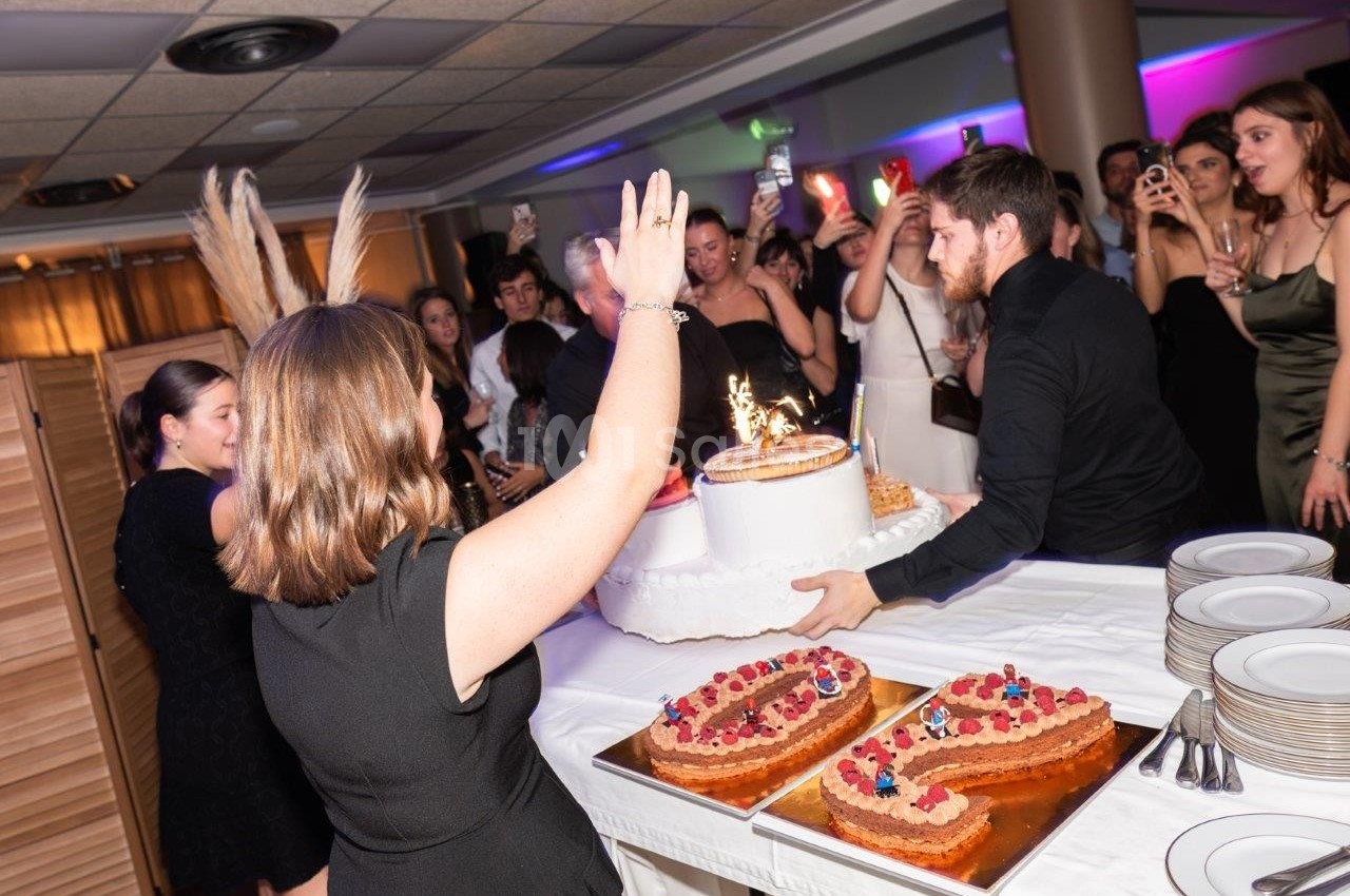 Un homme apporte un gâteau d'anniversaire avec des bougies allumées lors d'une fête entourée d'invités.