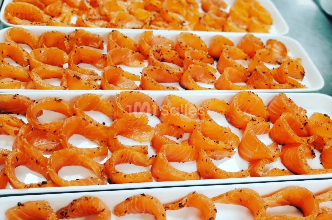 Tranches de saumon marinées disposées en rangées sur des plateaux blancs.