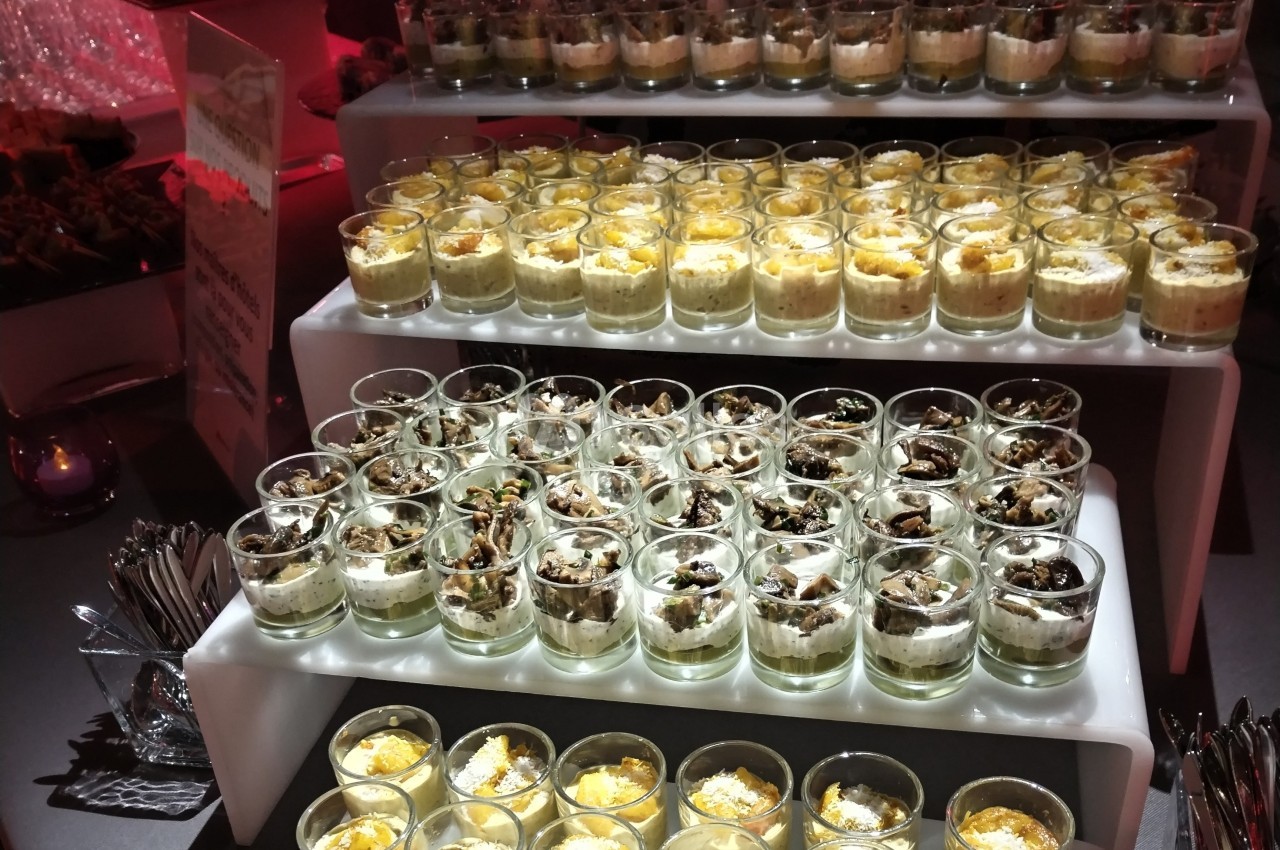Buffet de verrines variées disposées sur des étagères, avec des desserts et des entrées en portions individuelles.