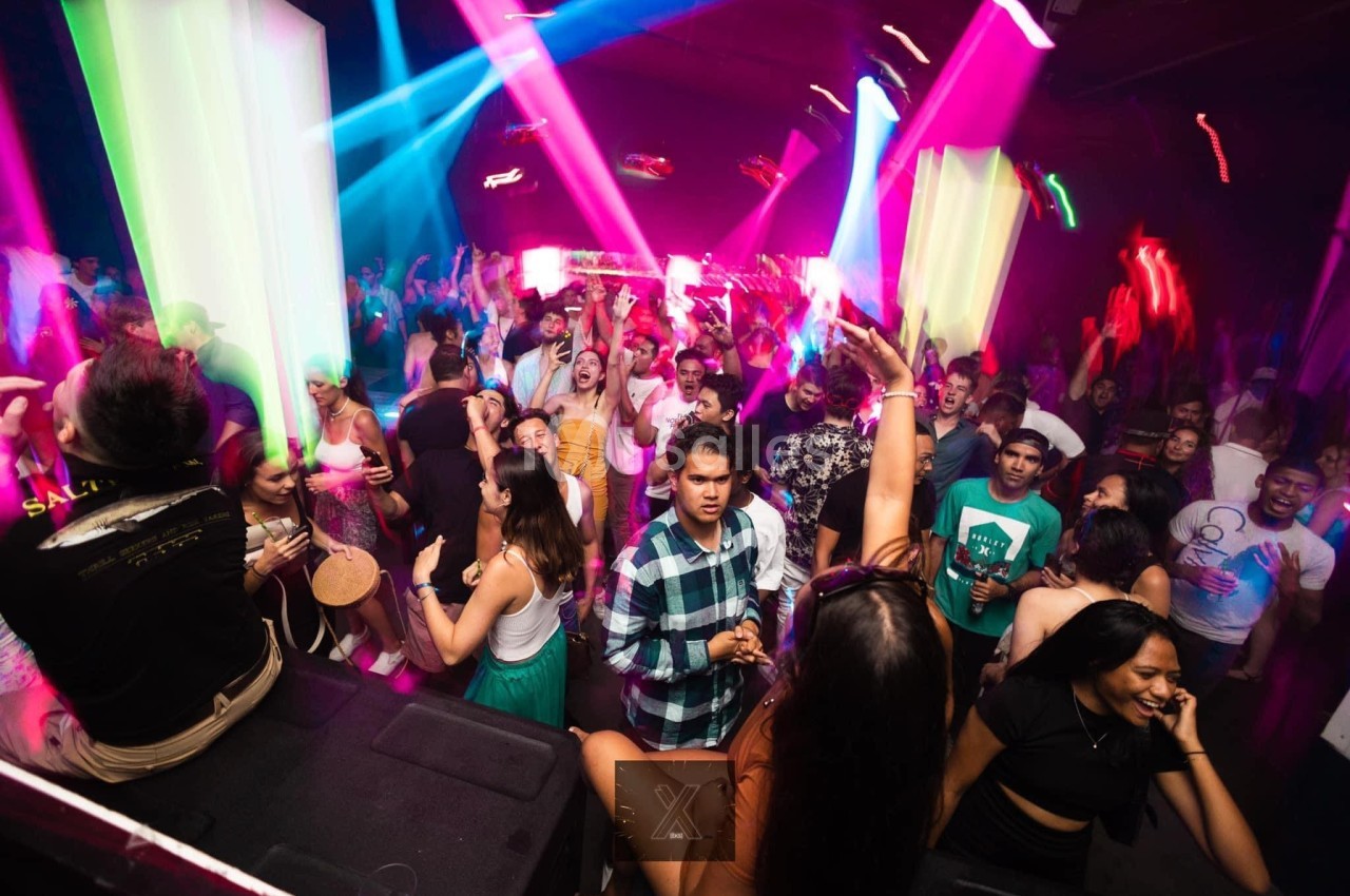 Personnes dansant et s'amusant dans une discothèque avec des lumières colorées et une ambiance festive.