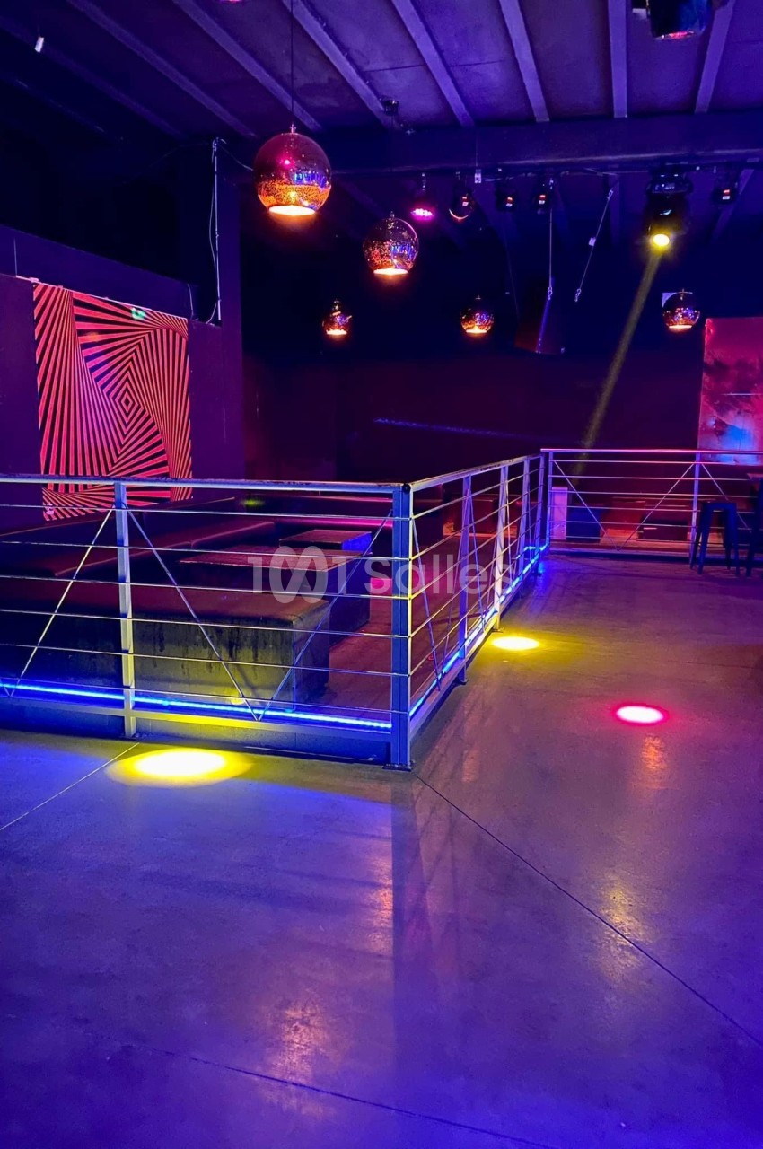 Salle vide avec piste de danse éclairée par des lumières colorées et décorations lumineuses au plafond.