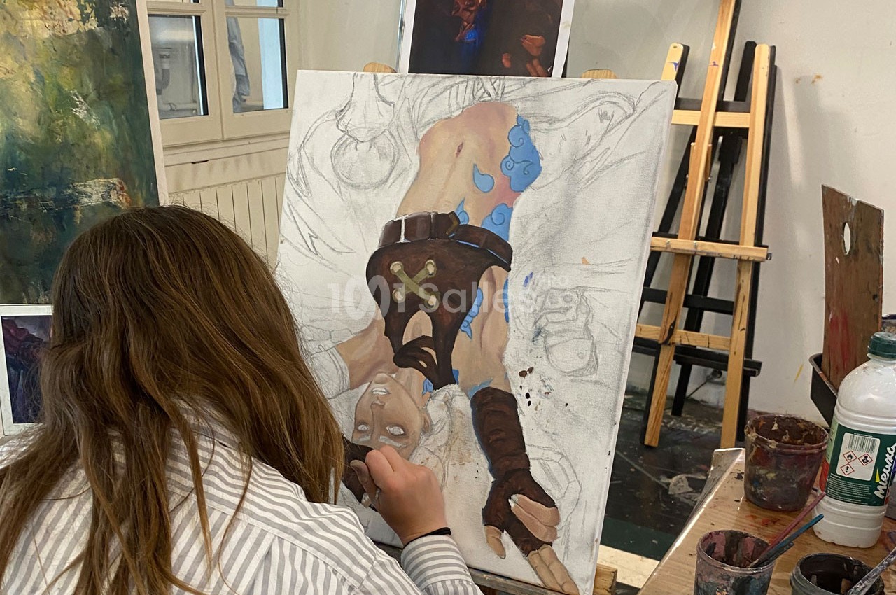 Une artiste peint une illustration détaillée d'un personnage fantastique sur une toile dans un atelier lumineux.