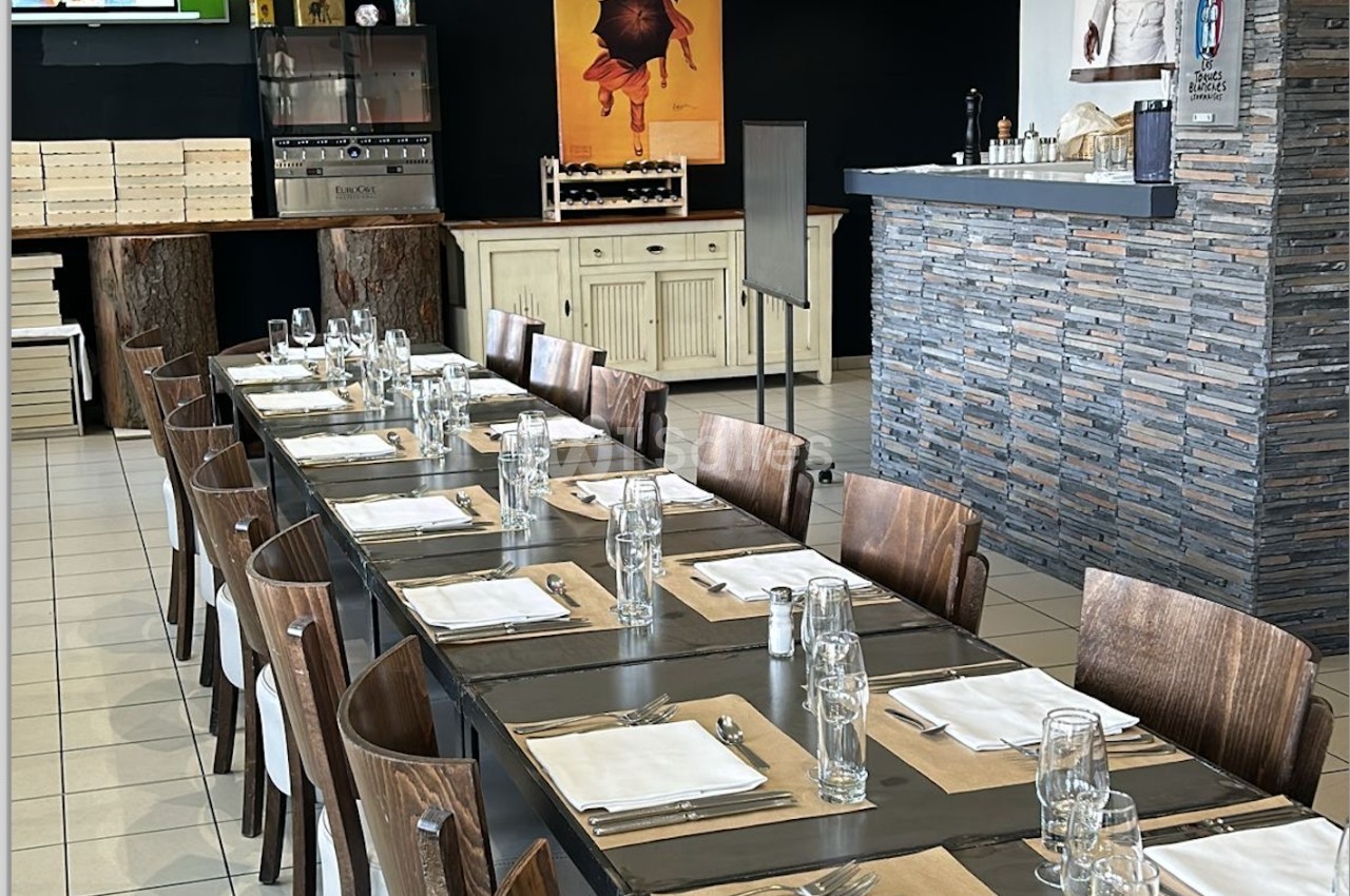 Grande table dressée avec des couverts et des verres dans un restaurant au décor moderne et chaleureux.