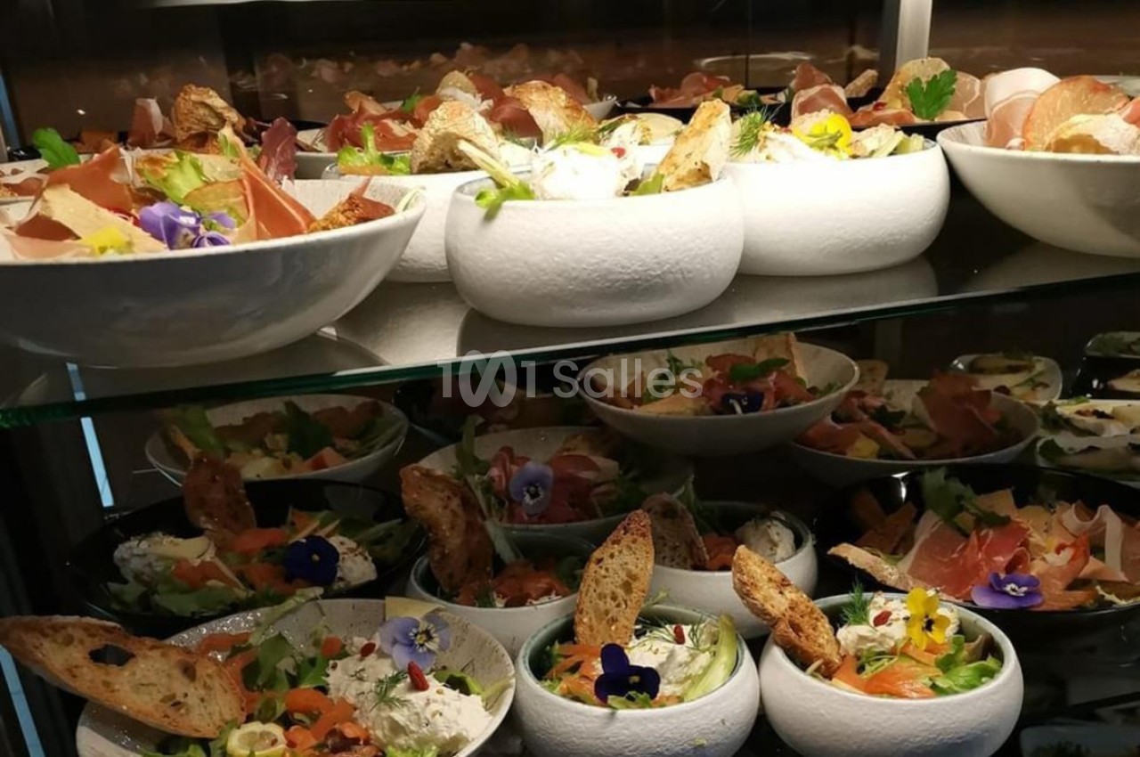 Assortiment de salades garnies de légumes, fleurs comestibles, pain grillé et charcuterie, disposées sur des étagères.