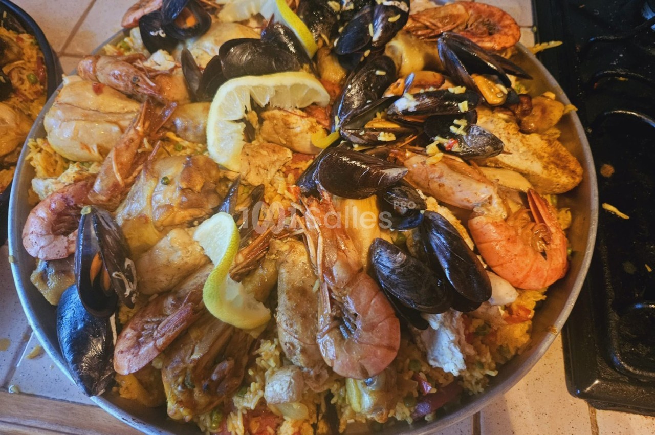 Plat de paella garni de fruits de mer, poulet, moules, crevettes et tranches de citron sur un lit de riz safrané.