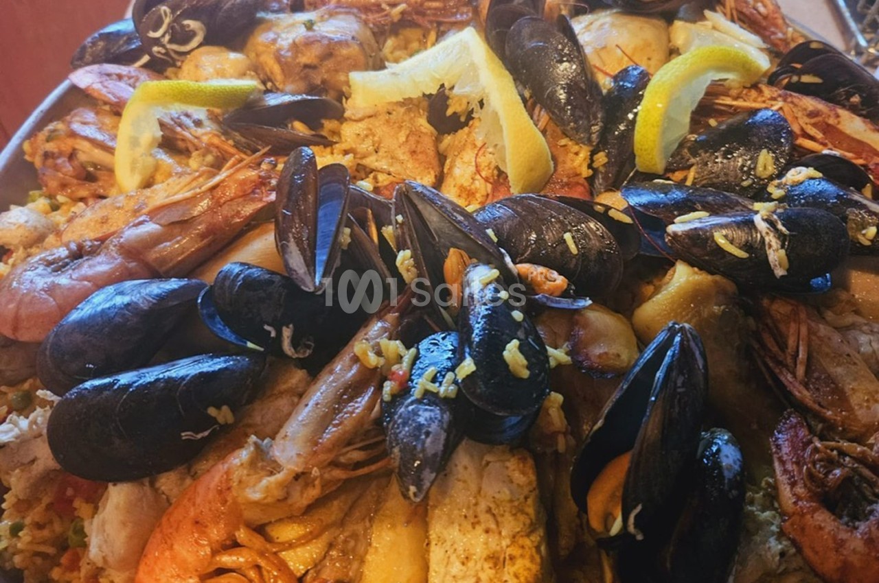 Assiette de fruits de mer variés avec moules, crevettes et quartiers de citron sur un lit de riz.
