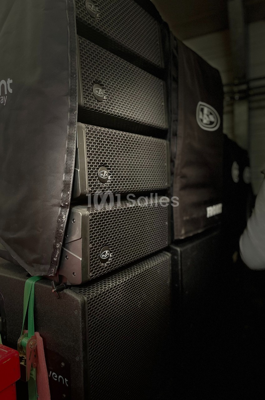 Enceintes de sonorisation empilées dans une configuration de type line array, partiellement couvertes par des housses.