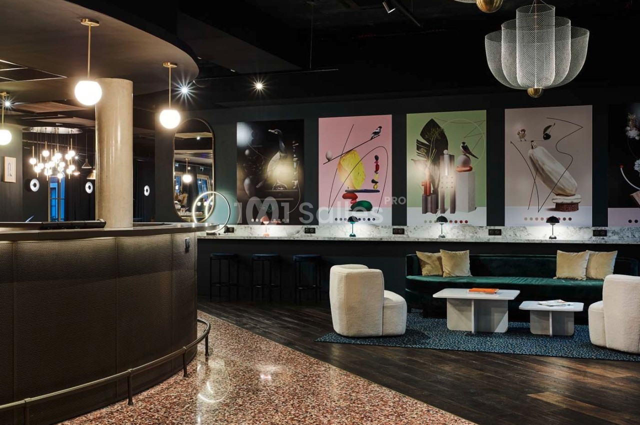 Intérieur d'un espace moderne avec comptoir arrondi, fauteuils, tables basses et décorations murales colorées.