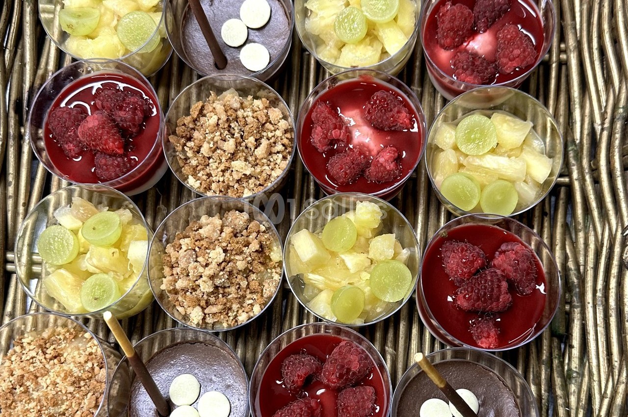 Desserts variés présentés dans des verrines, incluant fruits, crumble, mousse au chocolat et décorations.