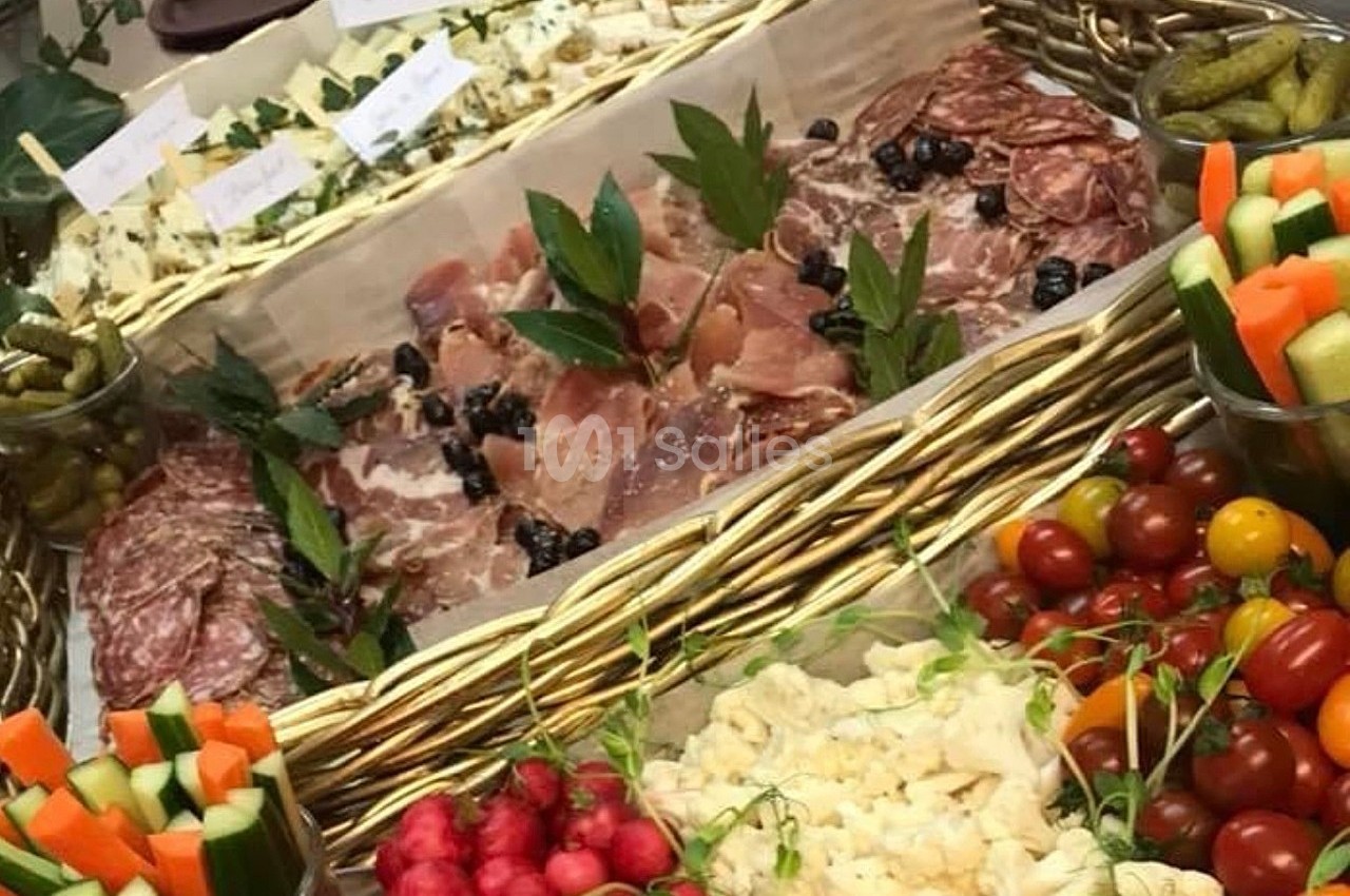 Plateau garni de charcuteries, fromages, légumes croquants, tomates cerises et cornichons, présenté dans un panier en osier.