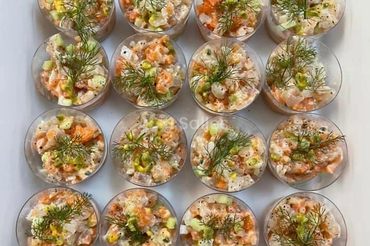 Verrines de tartare de poisson et légumes, garnies d'aneth, disposées en rangées sur une surface blanche.