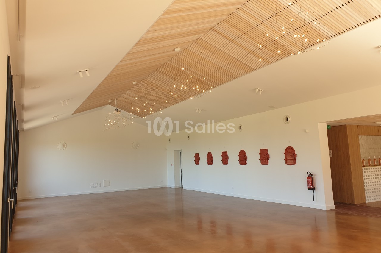 Salle lumineuse avec un sol en béton ciré, plafond en bois avec luminaires suspendus et murs décorés de motifs rouges.