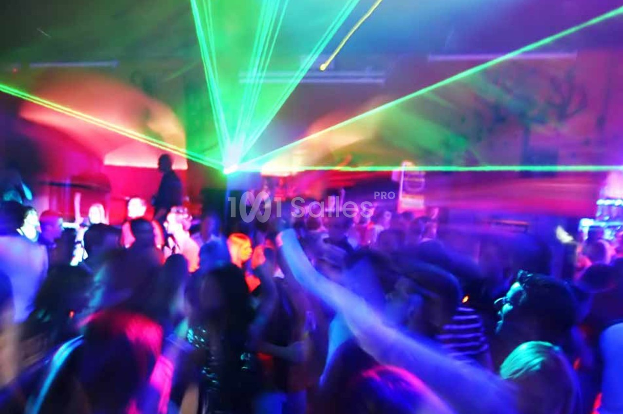 Foule dans une discothèque avec des lumières colorées et des faisceaux laser illuminant la salle.