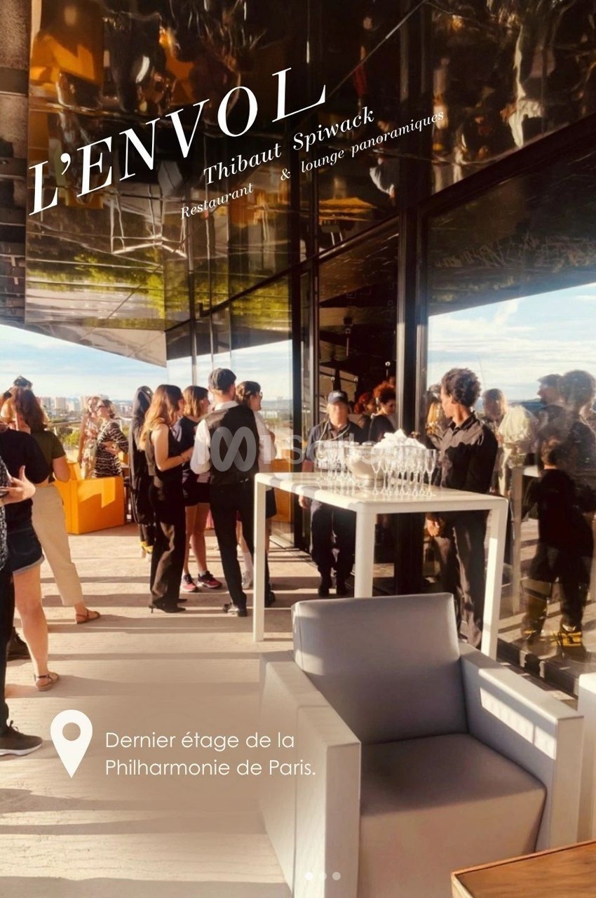 Terrasse animée d'un restaurant avec vue panoramique, serveurs et invités debout près d'une table dressée.
