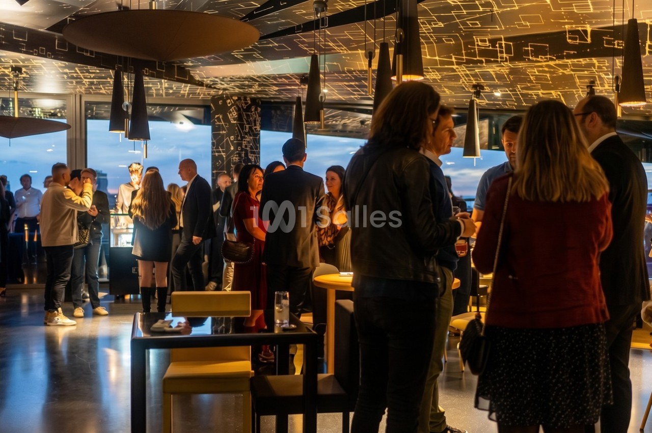 Personnes rassemblées dans un espace moderne et lumineux, discutant debout autour de tables hautes.