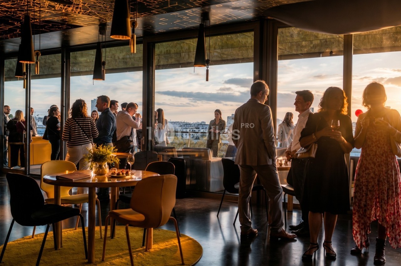 Groupe de personnes discutant dans un espace moderne avec vue panoramique sur la ville au coucher du soleil.