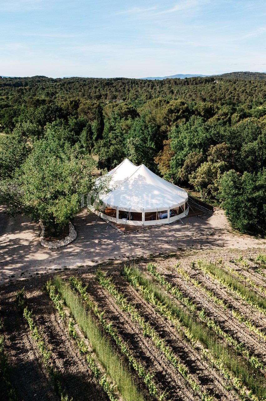 Chapiteau blanc conique implanté dans les vignes de Barbebelle, entouré de végétation méditerranéenne.