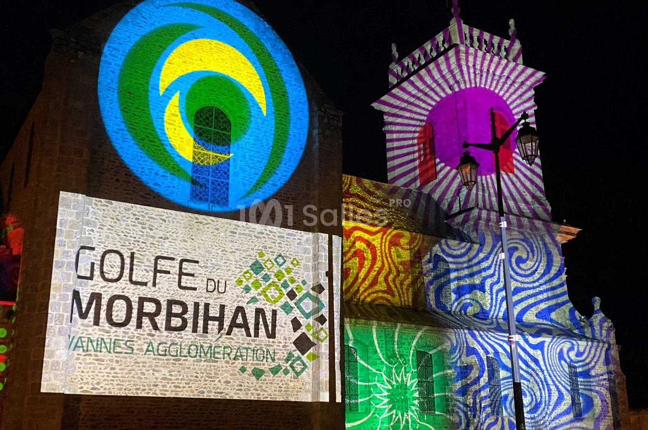 Projection lumineuse colorée sur la façade d'une église, mettant en avant le Golfe du Morbihan et Vannes Agglomération.