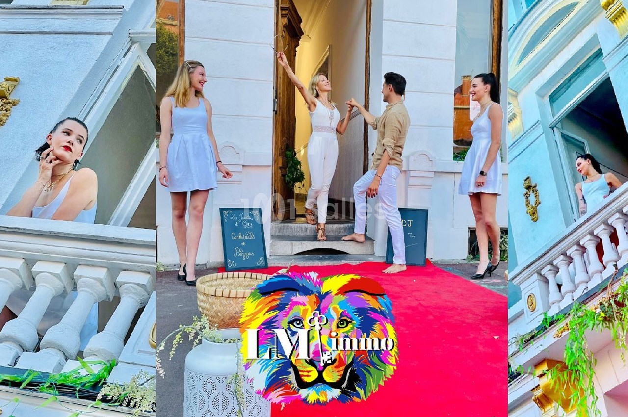 Quatre personnes posent sur un tapis rouge devant un bâtiment blanc avec des décorations colorées et un logo de lion.