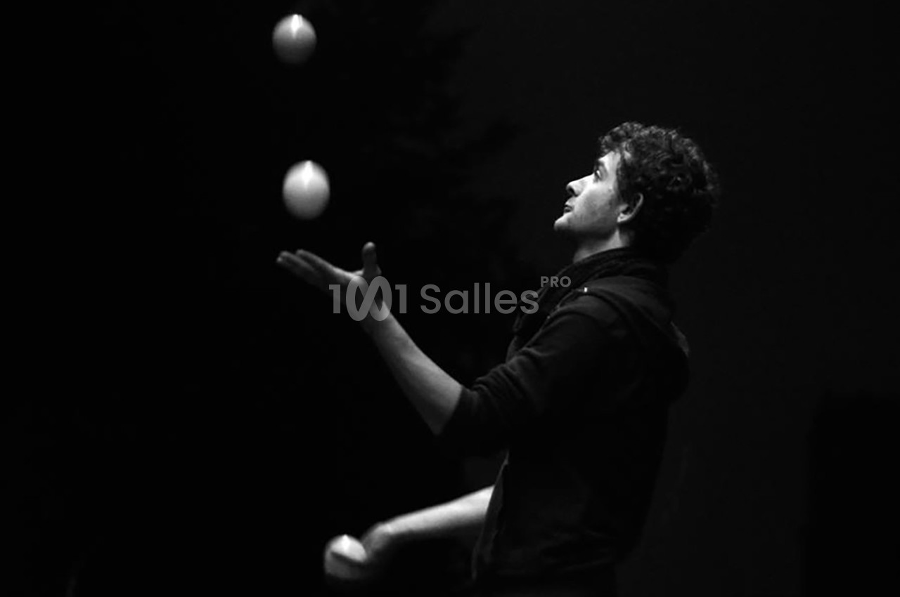 Un homme jongle avec trois balles dans un environnement sombre.