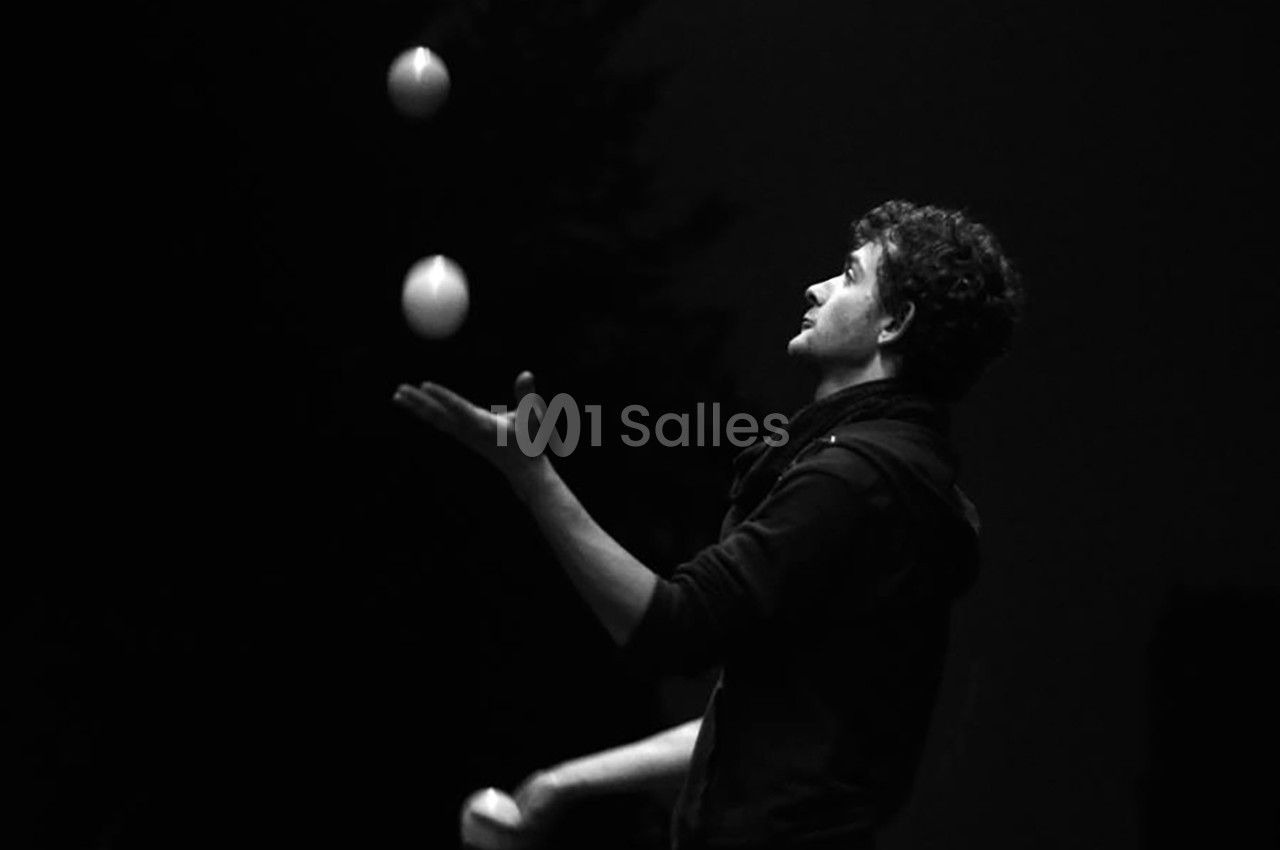 Un homme jongle avec trois balles dans un environnement sombre.
