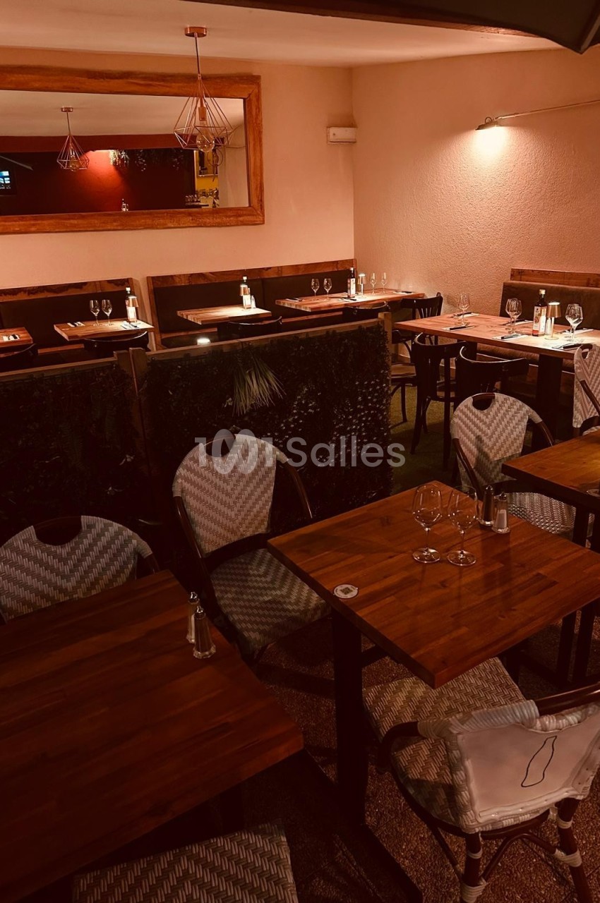 Salle de restaurant avec tables en bois, chaises tressées et éclairage tamisé, ambiance chaleureuse et intimiste.