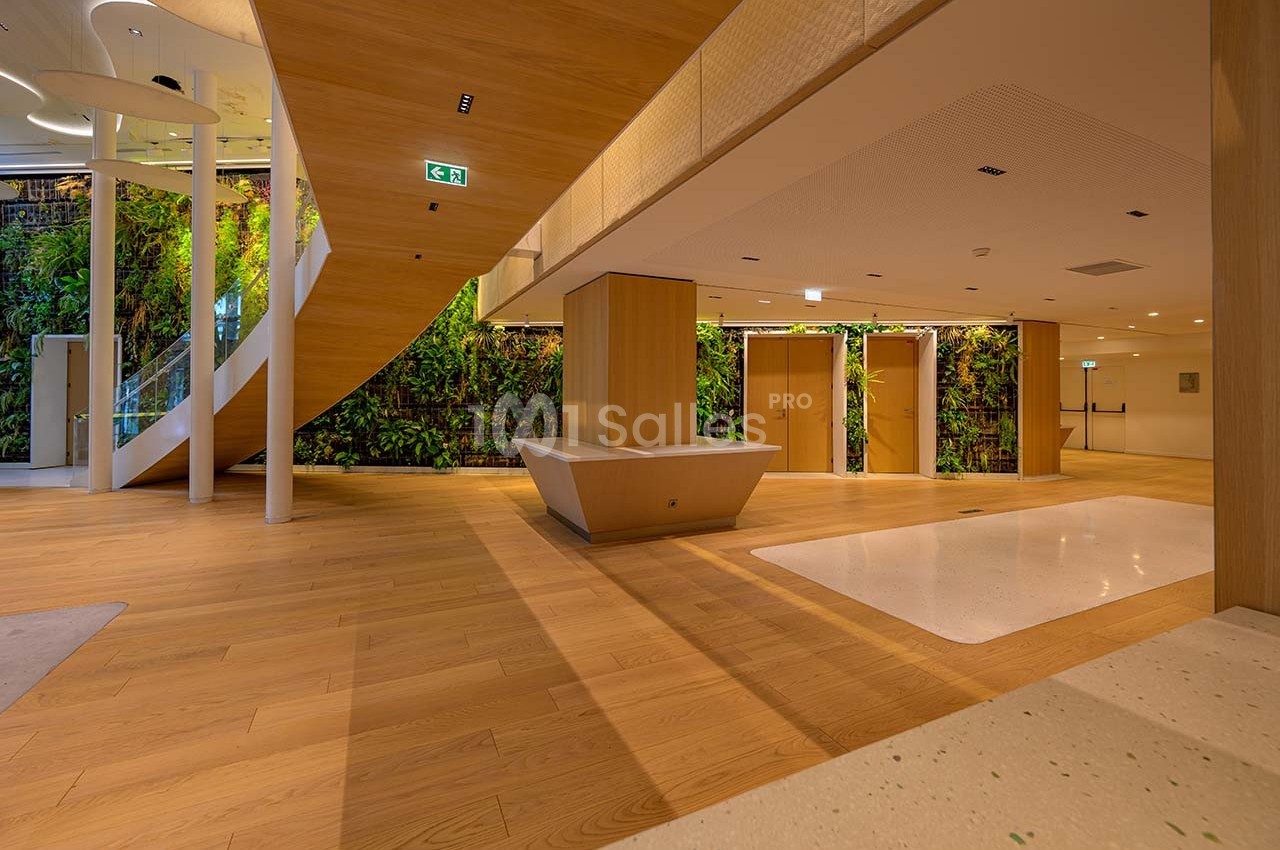 Intérieur moderne avec sol en bois, escalier en colimaçon, mur végétal et éclairage doux.