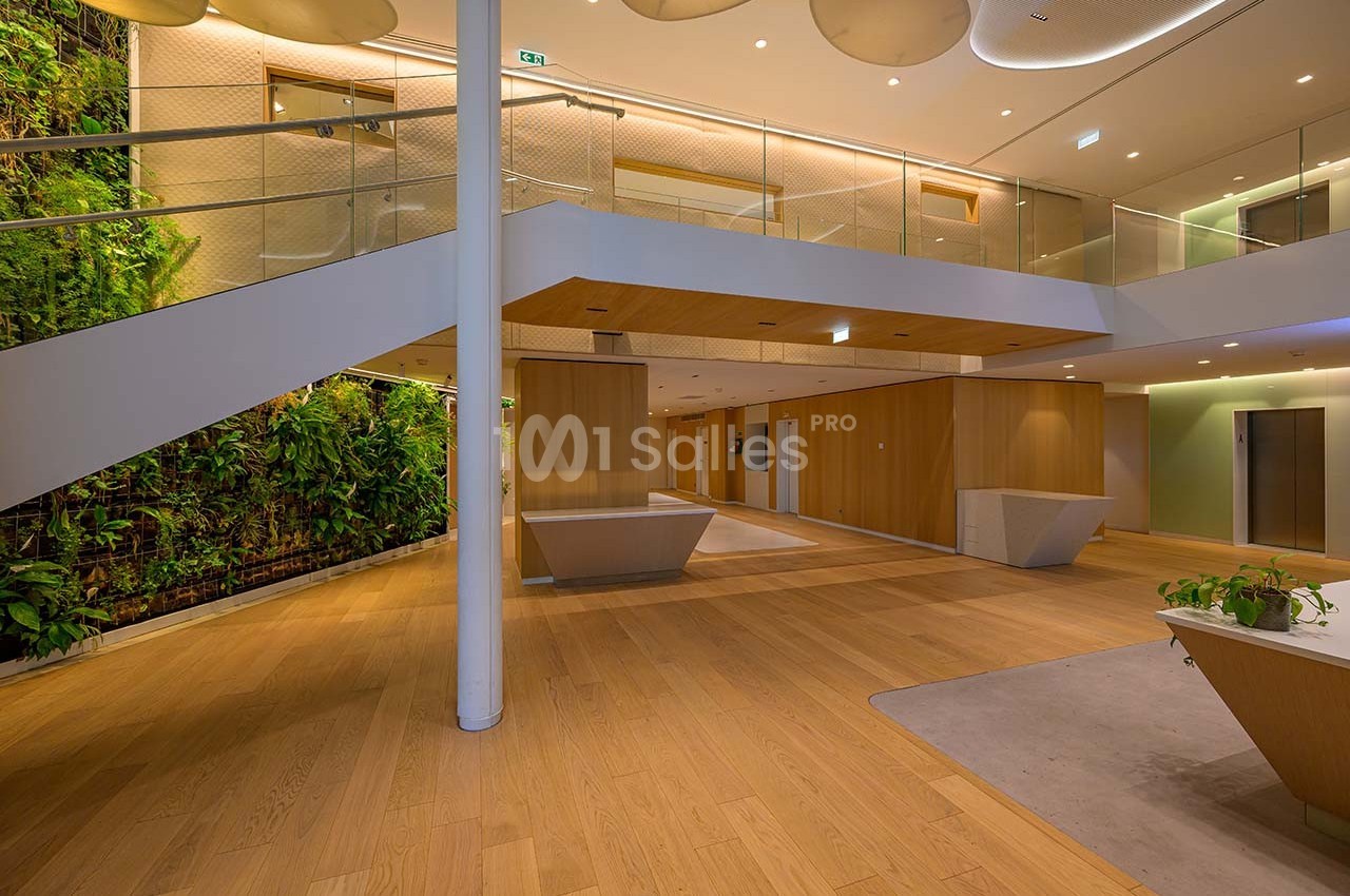 Intérieur moderne avec escalier, murs en bois, sol en parquet et mur végétal dans un espace lumineux.