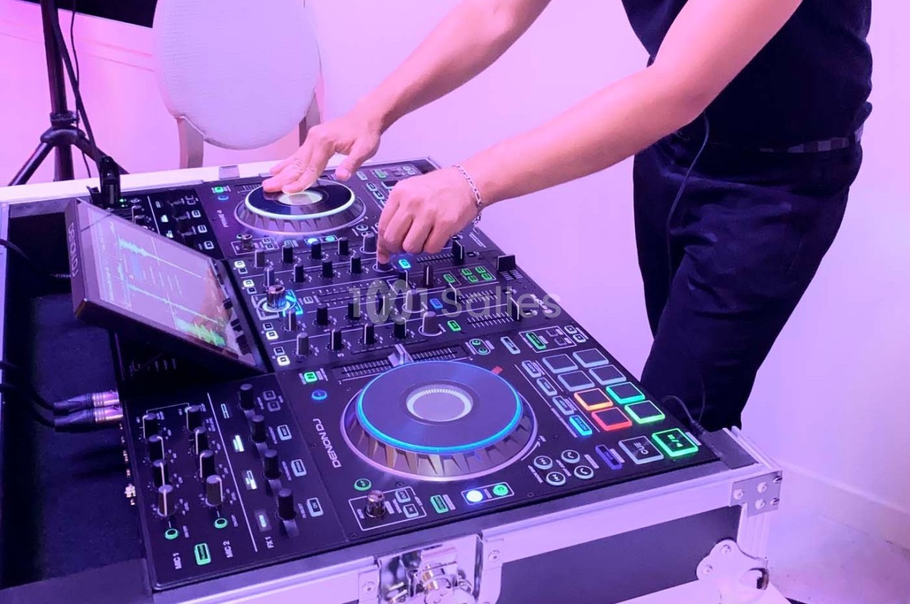Un DJ mixant de la musique sur une table de mixage lumineuse avec des commandes et des écrans tactiles.