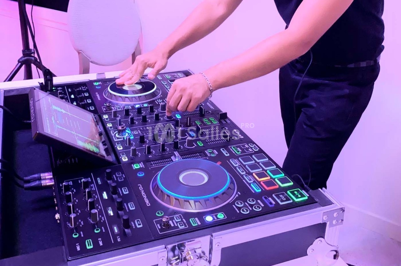 Un DJ mixant de la musique sur une table de mixage lumineuse avec des commandes et des écrans tactiles.