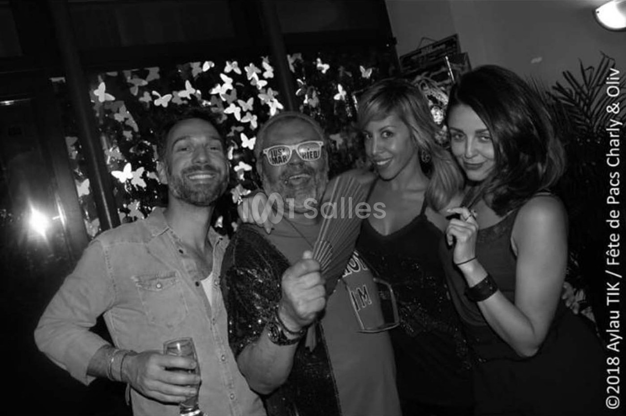 Quatre personnes posent ensemble lors d'une fête, souriantes et détendues, dans un cadre décoré de papillons lumineux.