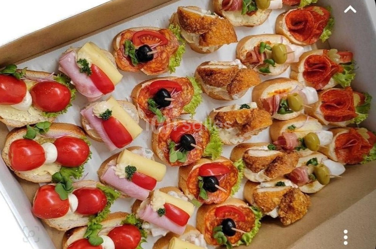 Plateau de canapés variés garnis de légumes, charcuteries, fromages et olives, disposés sur des tranches de pain.