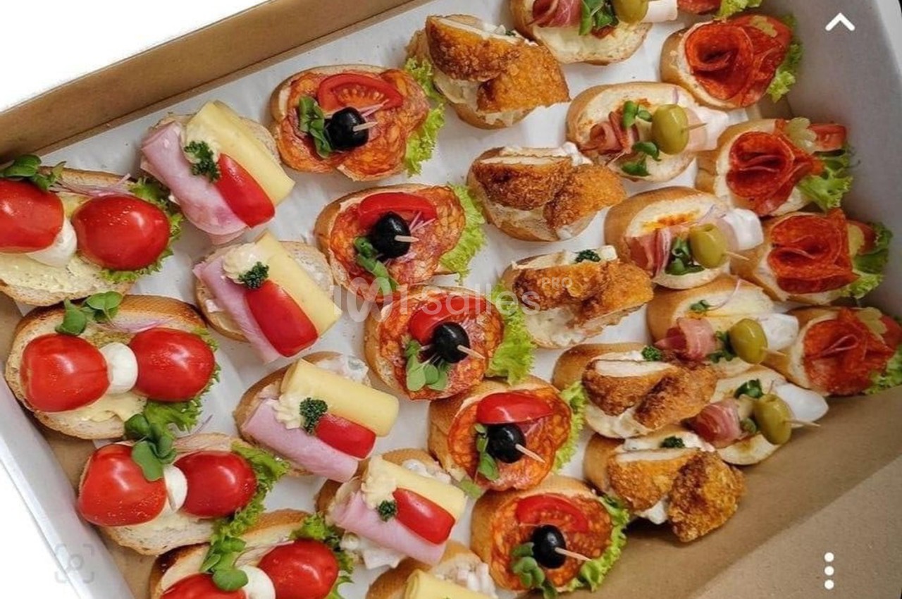 Plateau de canapés variés garnis de légumes, charcuteries, fromages et olives, disposés sur des tranches de pain.