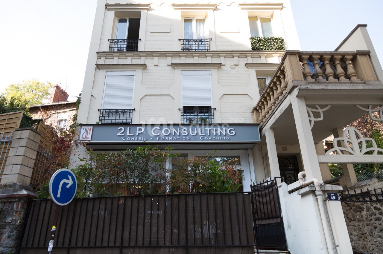 Façade d'un bâtiment abritant une entreprise de conseil, avec un panneau ’2LP Consulting’ et un panneau de signalisation.