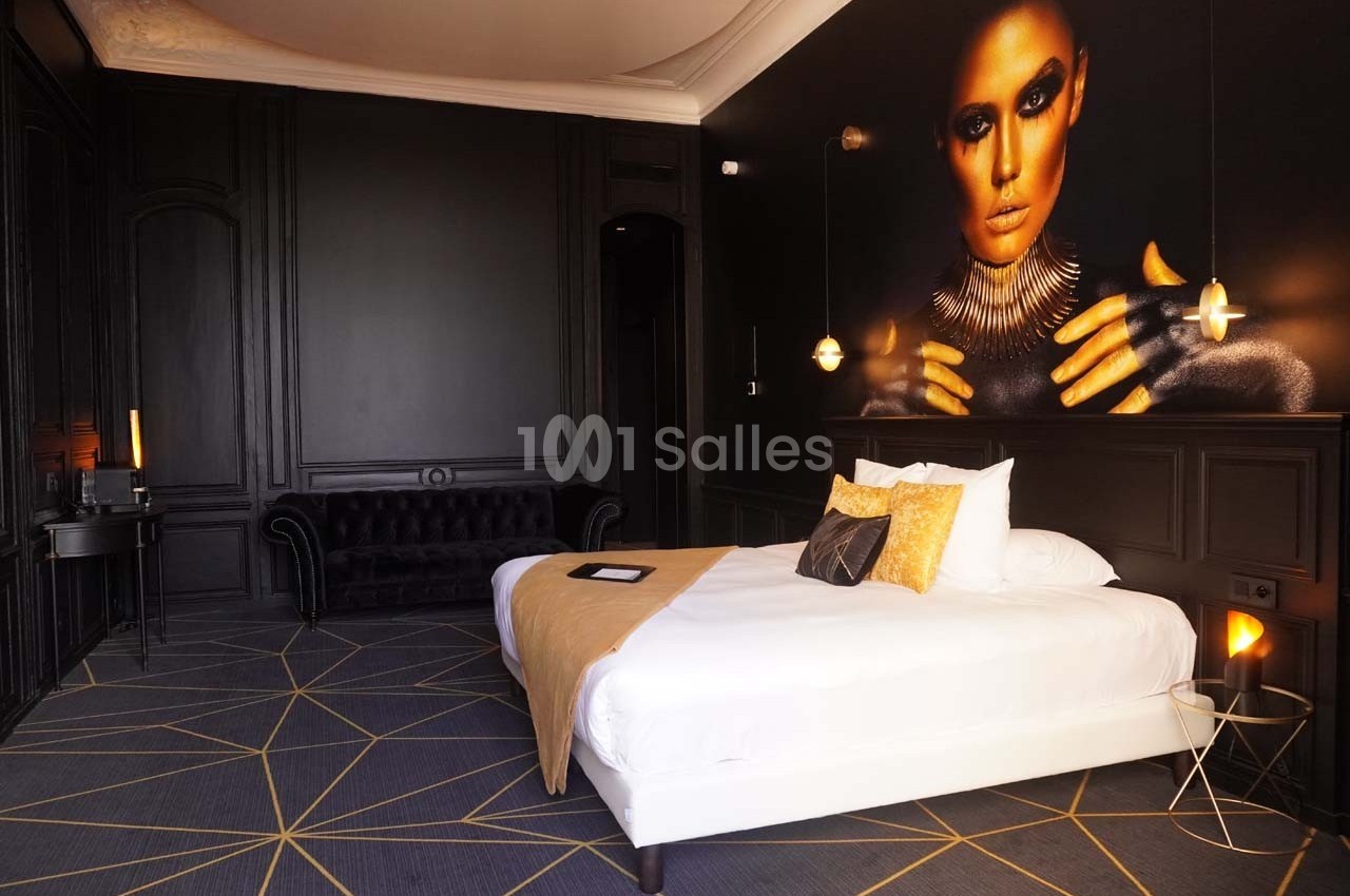 Chambre moderne avec lit double, décor sombre, mur orné d'une grande photo artistique et éclairage tamisé.