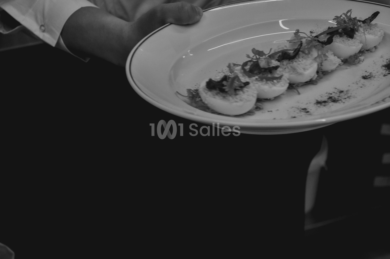 Un serveur présente une assiette contenant plusieurs œufs farcis garnis de feuilles et d'épices.