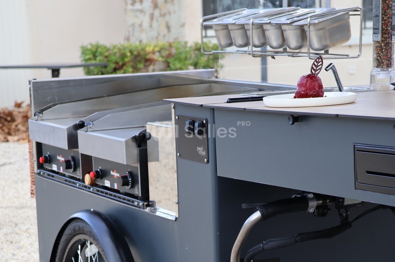 Chariot de cuisine mobile avec plaques de cuisson et condiments, une pomme d'amour posée sur le comptoir.